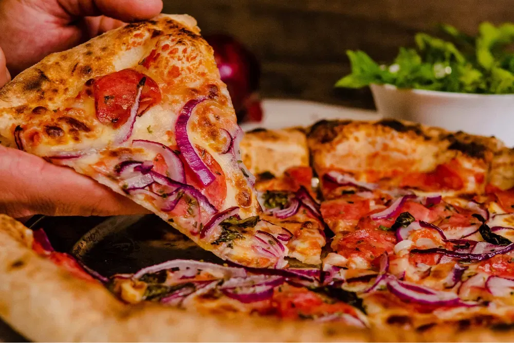 a hand holding a slice of pizza